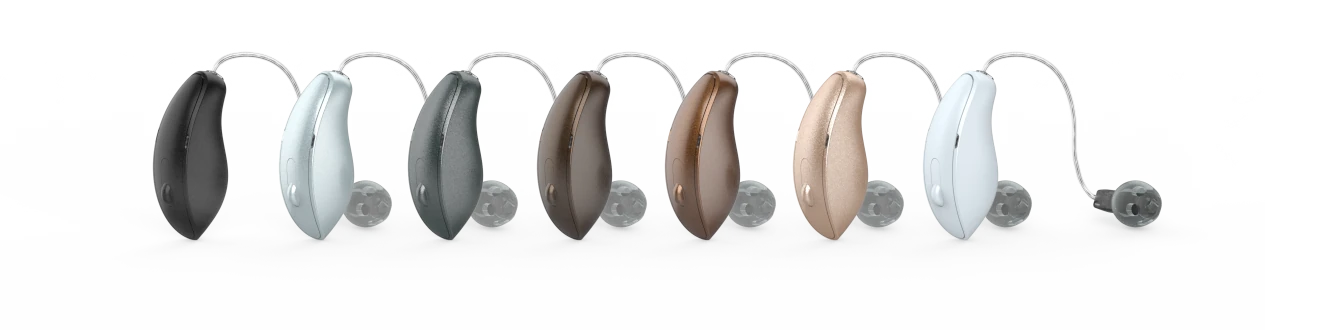 Mehrere moderne Hörgeräte in verschiedenen Farben sind nebeneinander auf weißem Hintergrund zu sehen.